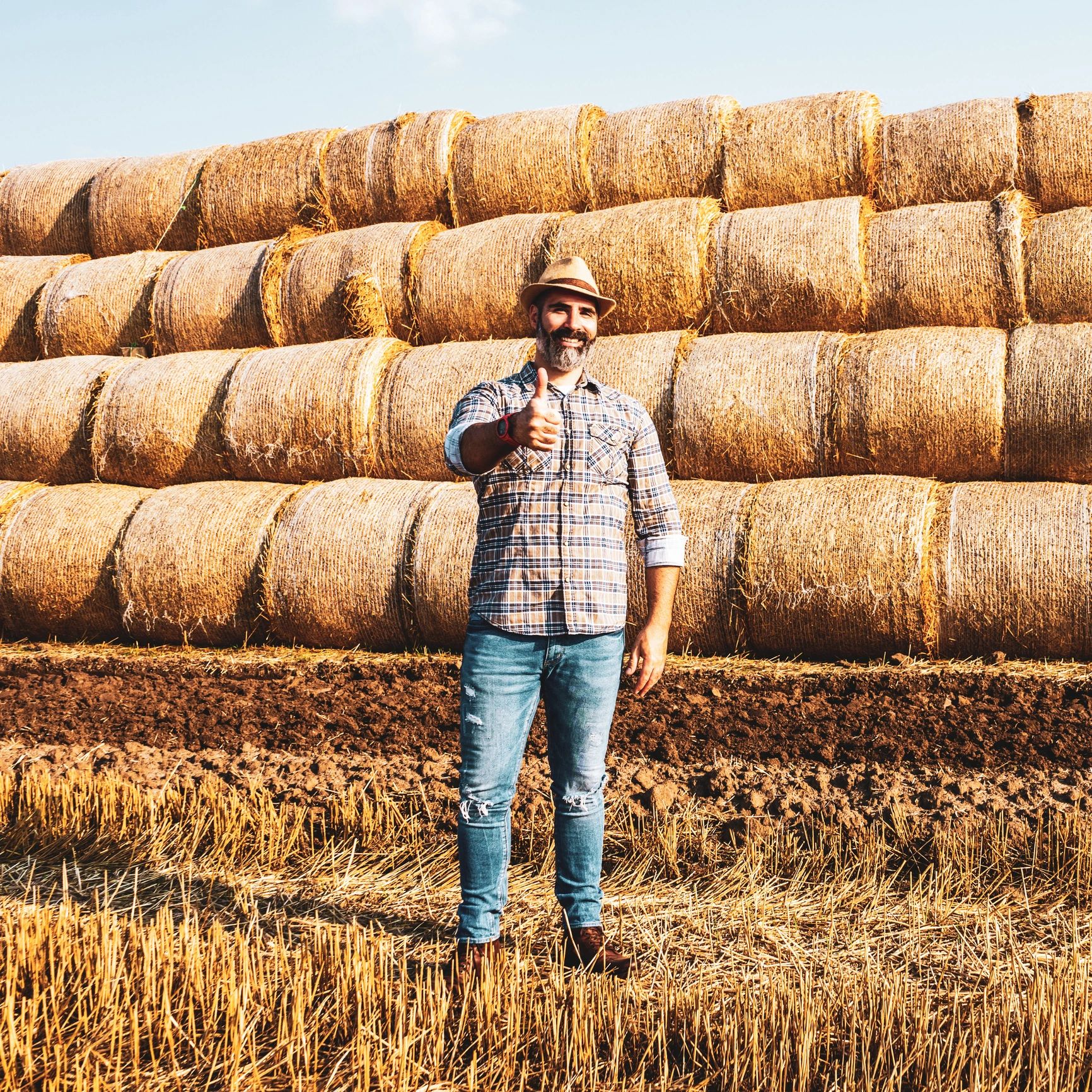 Farmer standing beside hay bales